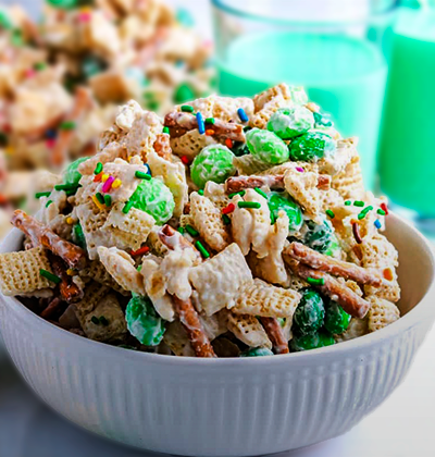 a bowl of st patricks day themed snack of chex mix, chocolate, and lucky charms